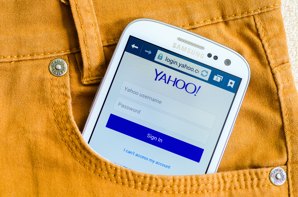 Yahoo smartphone logo on a phone screen in pocket of yellow trousers