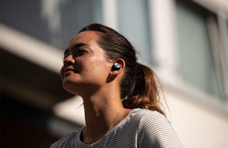 Woman wearing the Sennheiser Momentum True Wireless earbuds. 