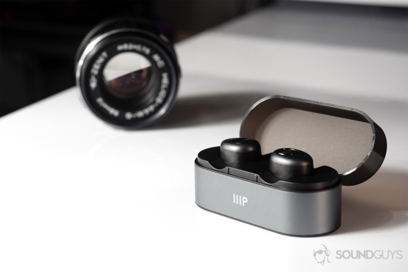 Monoprice cheap true wireless earbuds in case an din front of a black vintage lens.