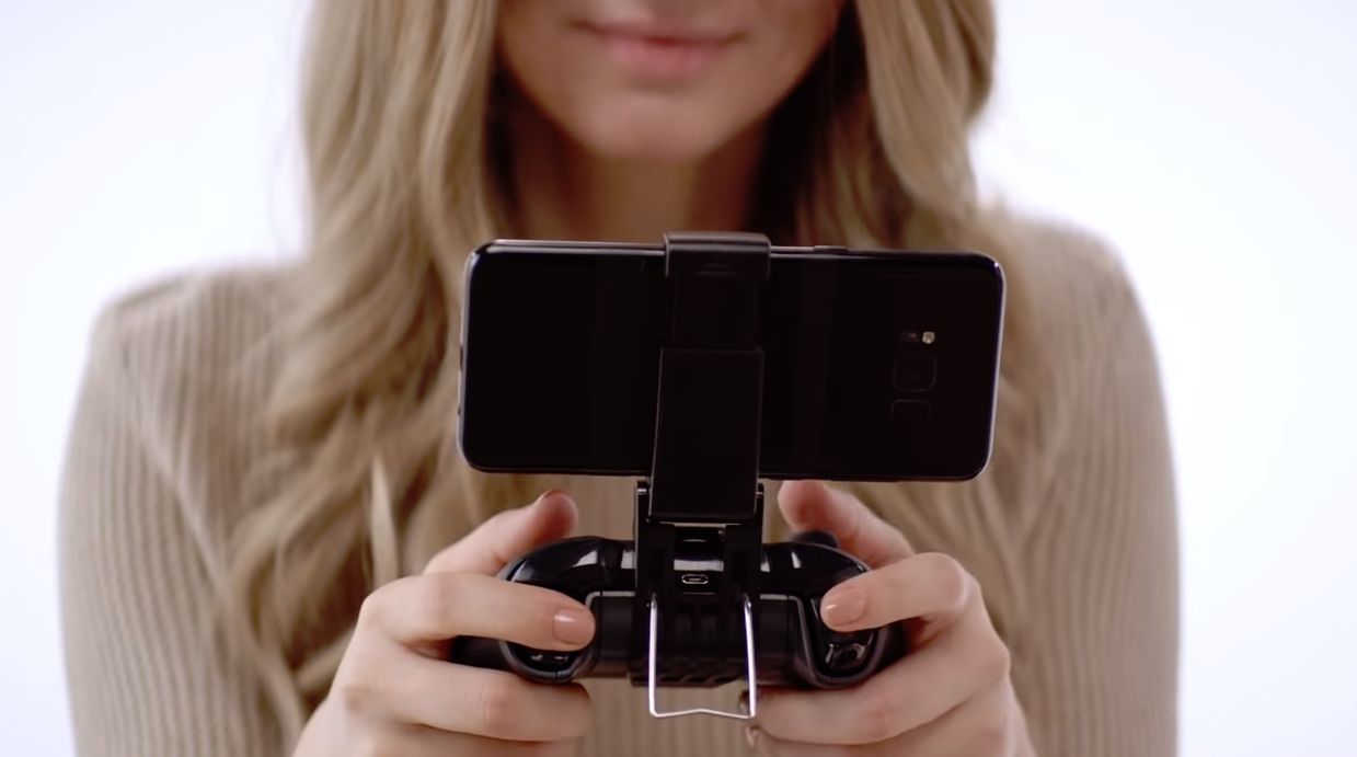 Photo of a smartphone on a game controller held by a woman - Microsoft's Project xCloud cloud gaming