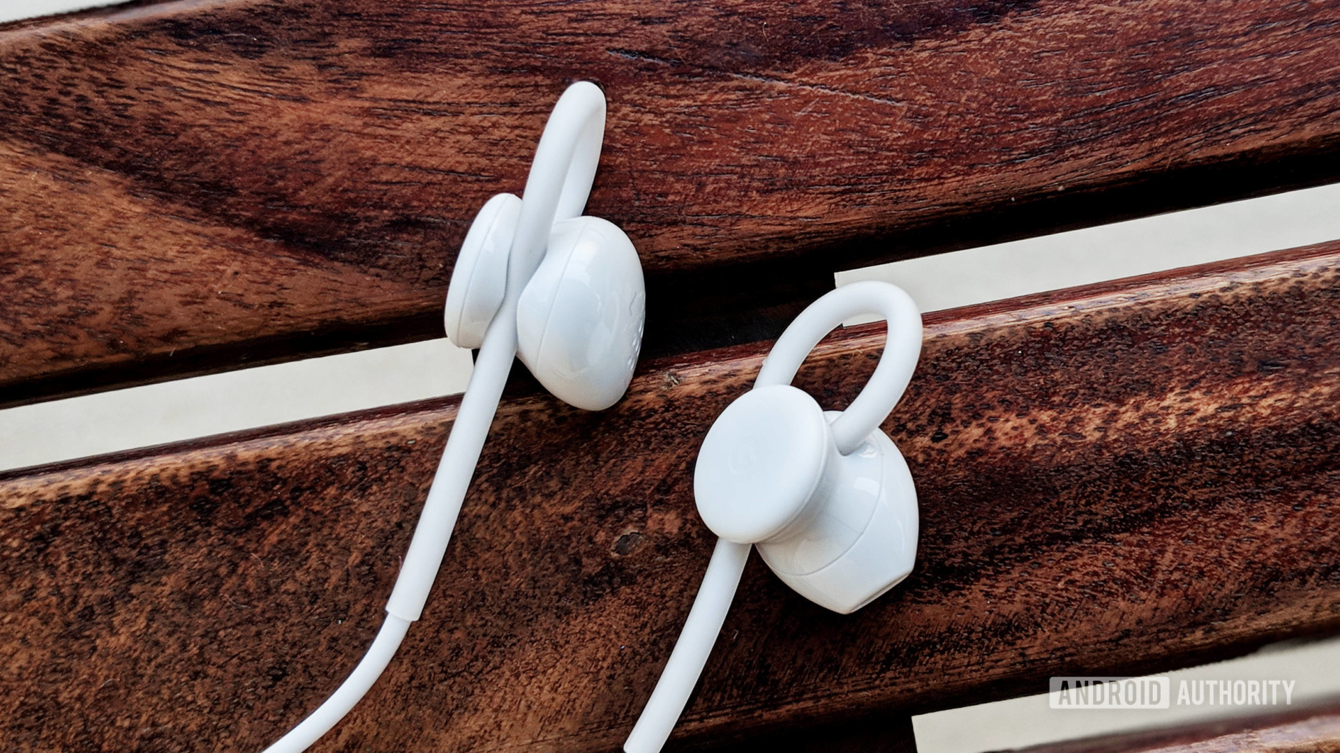 Pixel USB-C earbuds in white on wooden surface.
