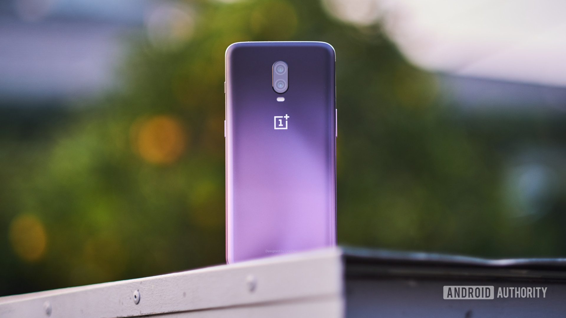 The OnePlus 6T in Thunder Purple outdoors on a wall.