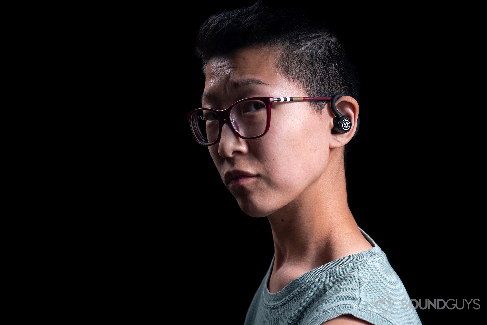 JLab Epic Air Elite: A woman wearing the earbuds against a black background.
