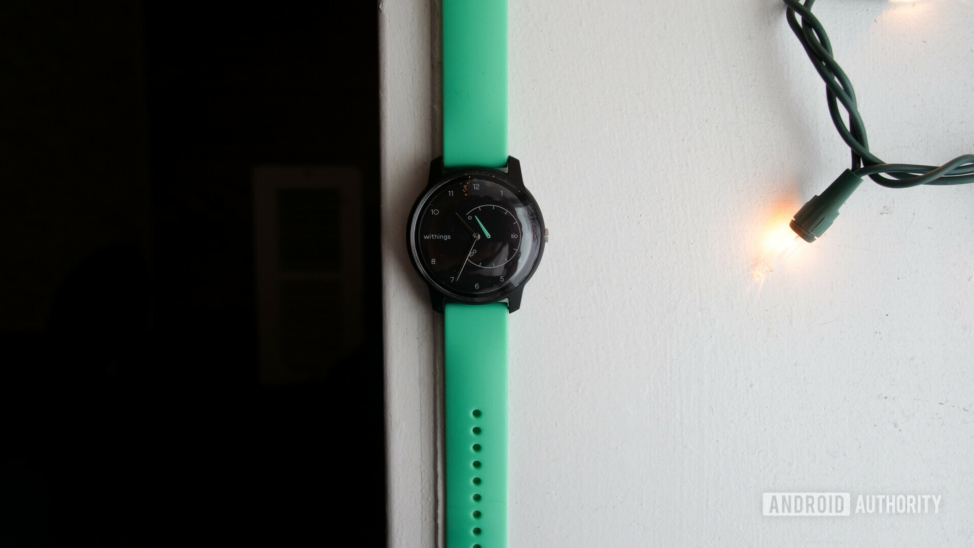 Photo of a customized green and black Withings Move on a white table.