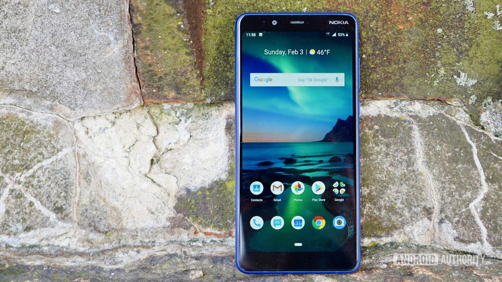 The front side of a Blue Nokia 3.1 Plus layed on a gray stone.