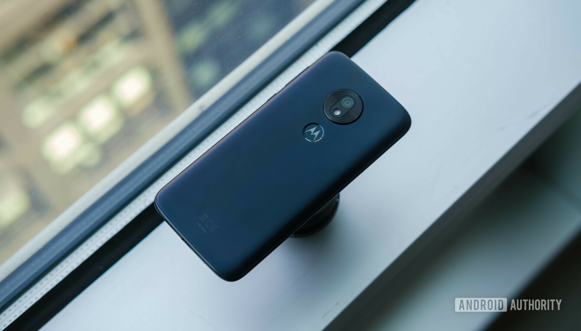 Backside of the new Motorola G7 Play in dark blue color laying face down in front of a window.