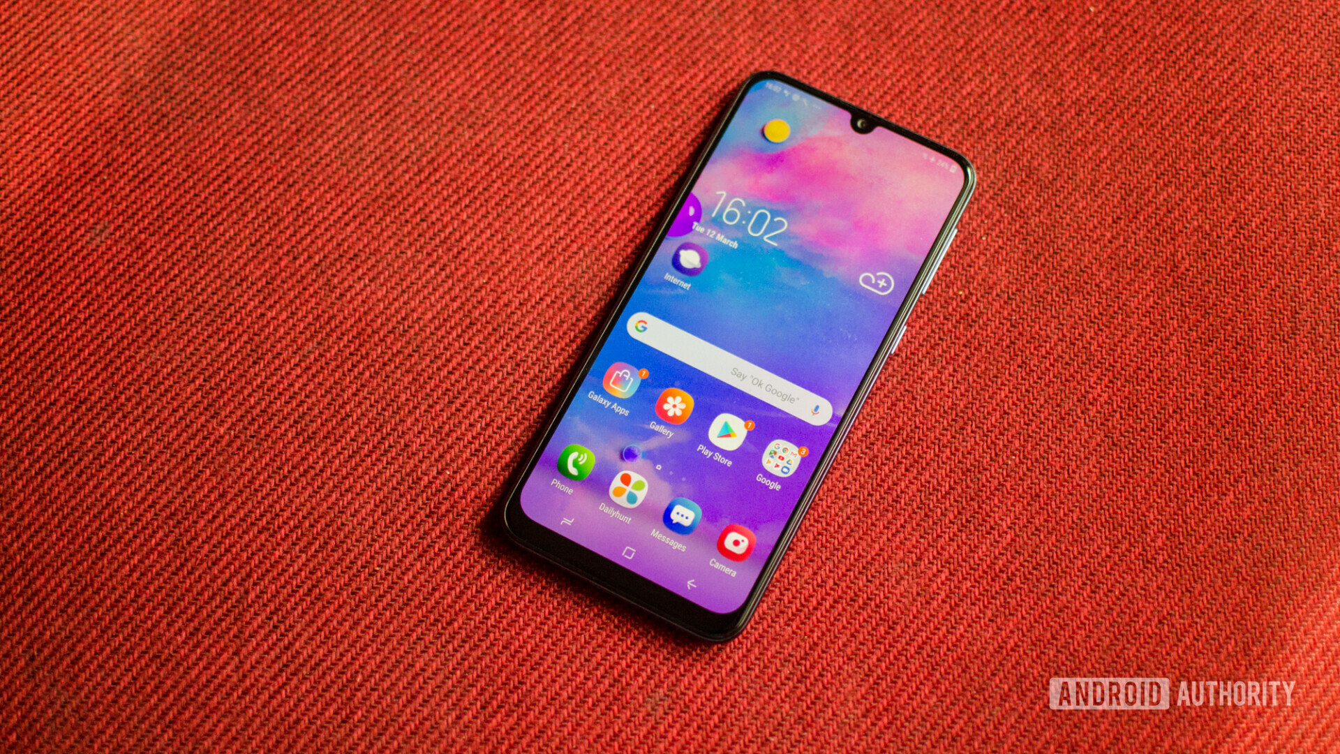 Front side of the Samsung Galaxy M30 with the display turned on showing the default homescreen.