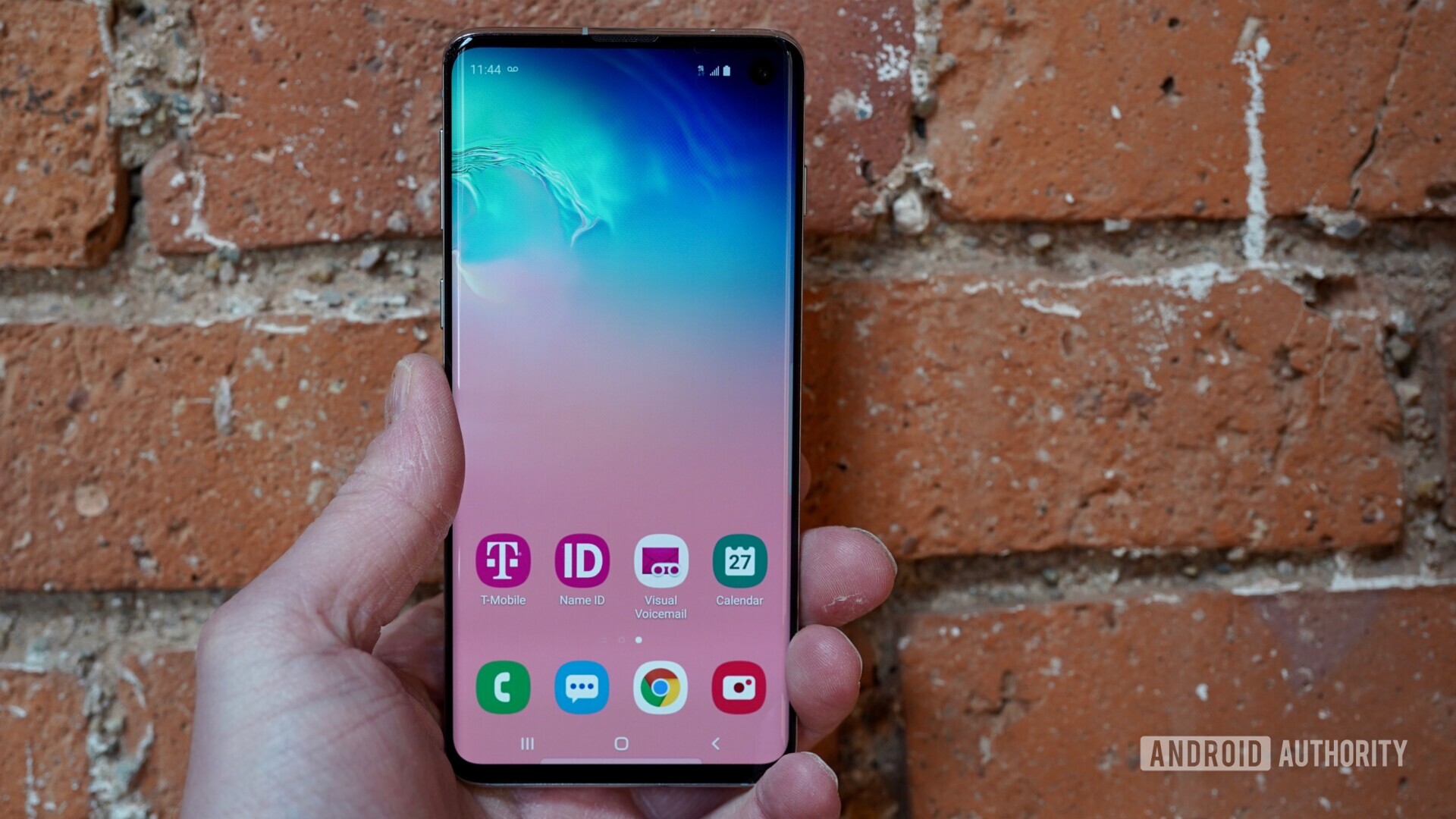 Front side of the Samsung Galaxy S10 held in hand with the display turned on.