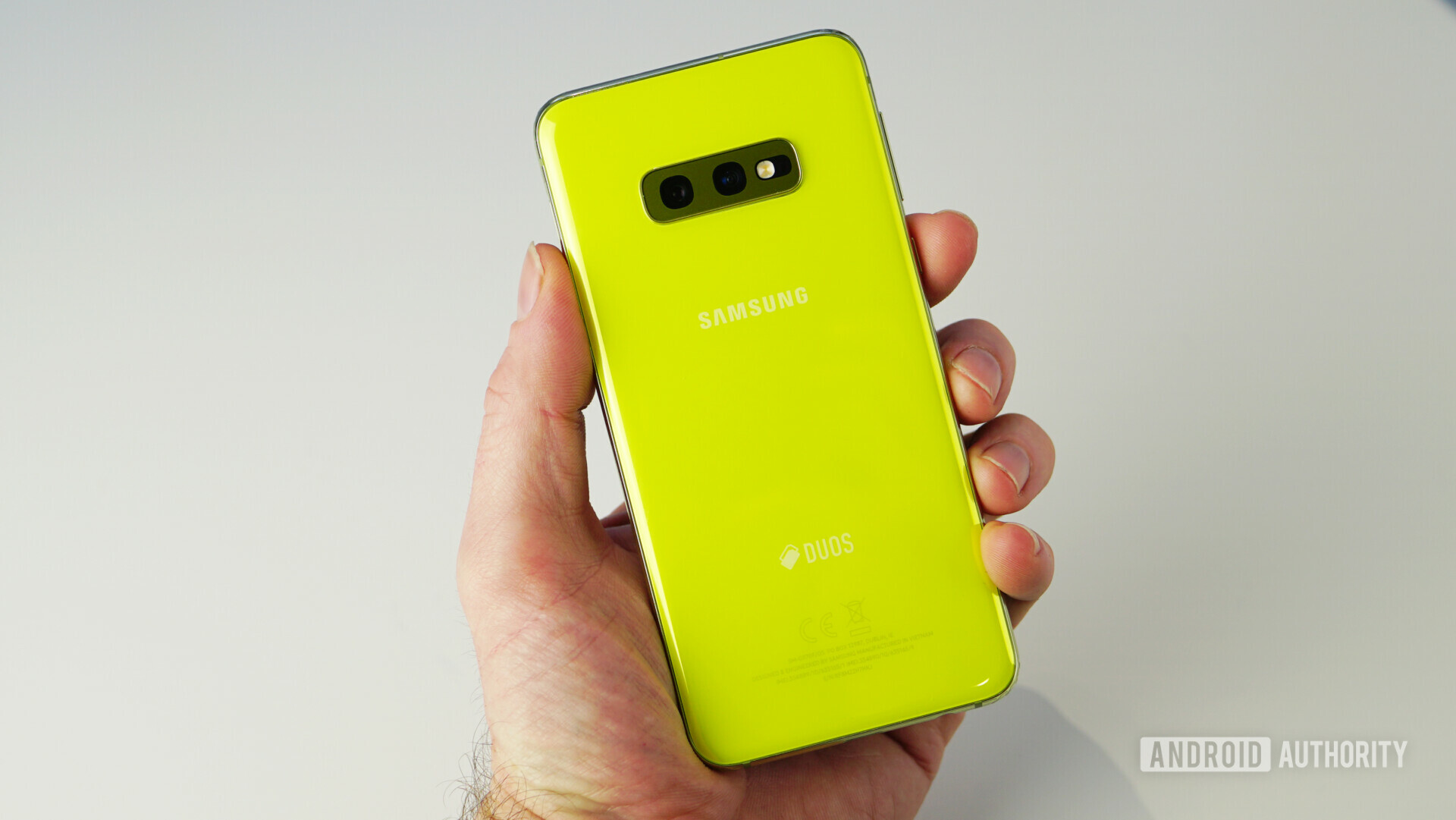 A hand holding the Samsung Galaxy S10e showing the back view.