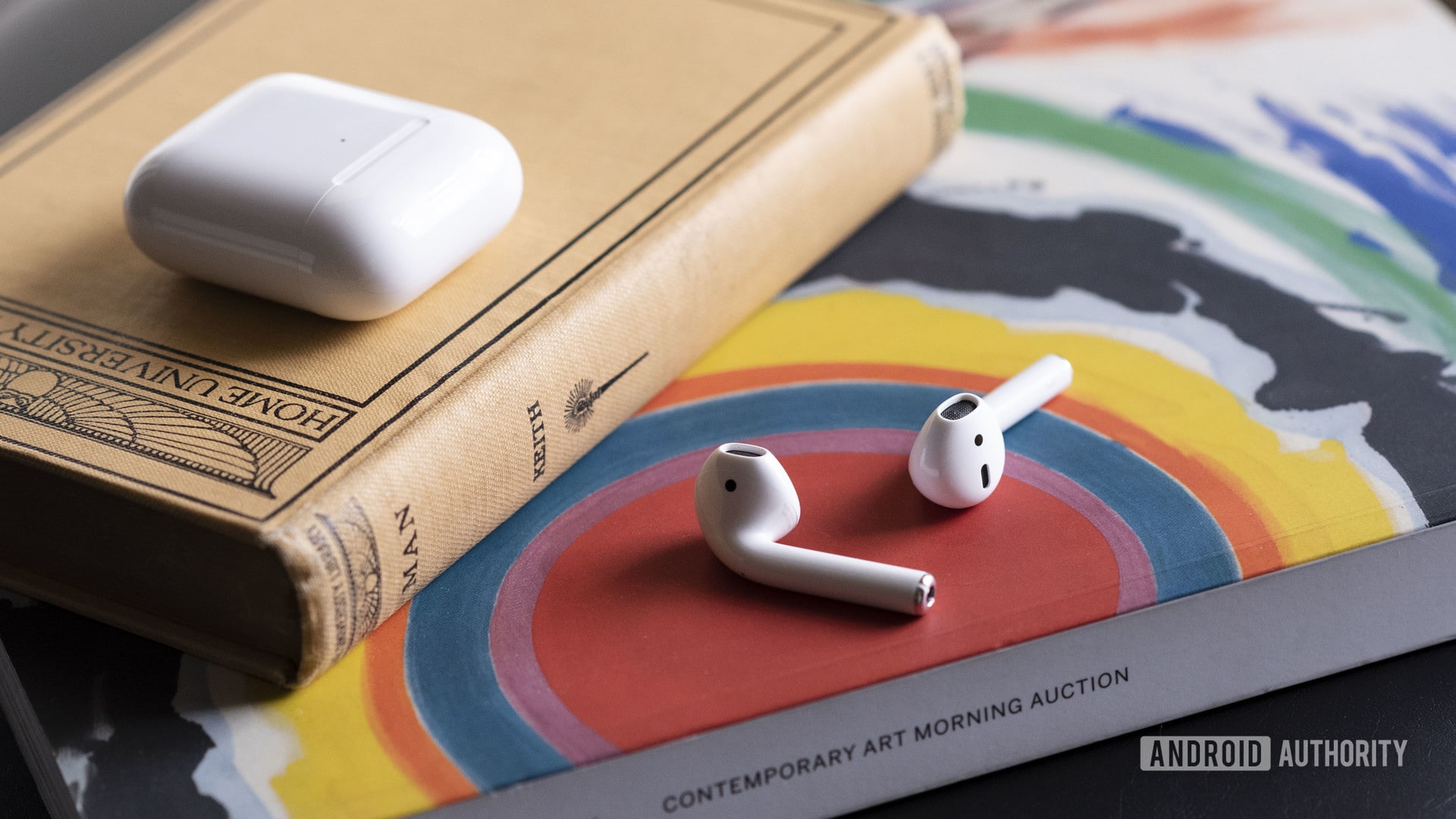 Apple new AirPods 2 outside of the case resting on a book.