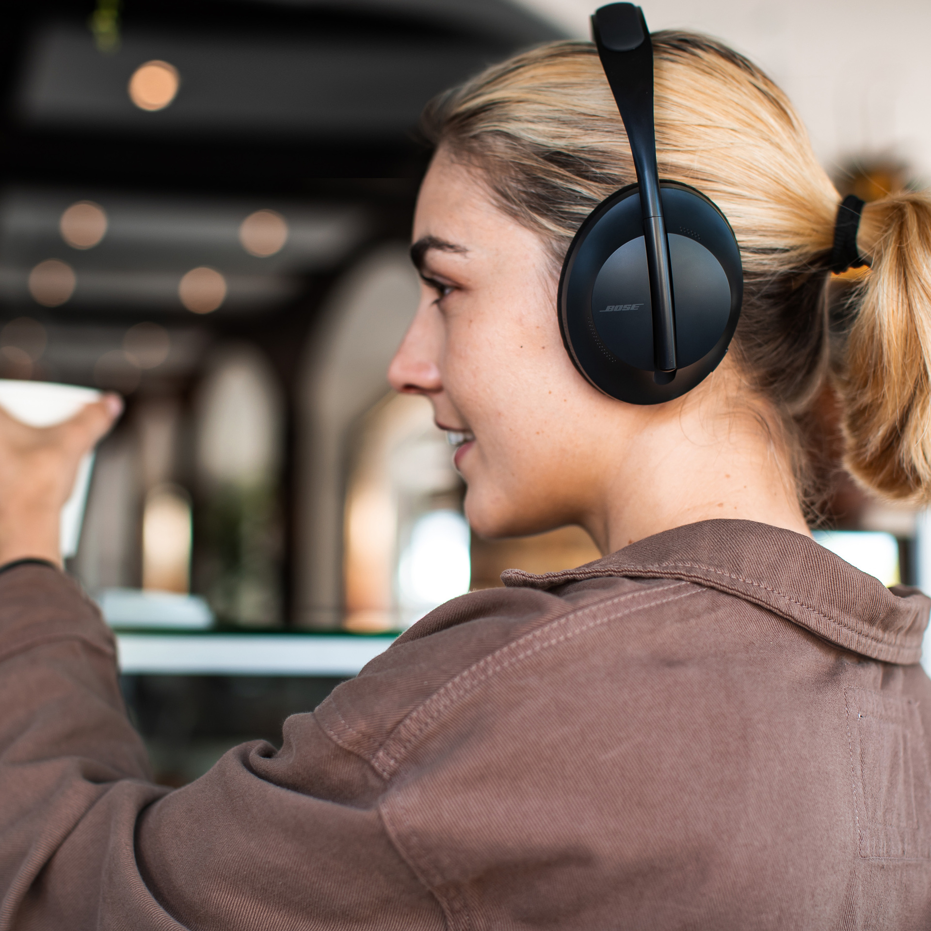 A woman wearing the Bose Headphones 700 in black.