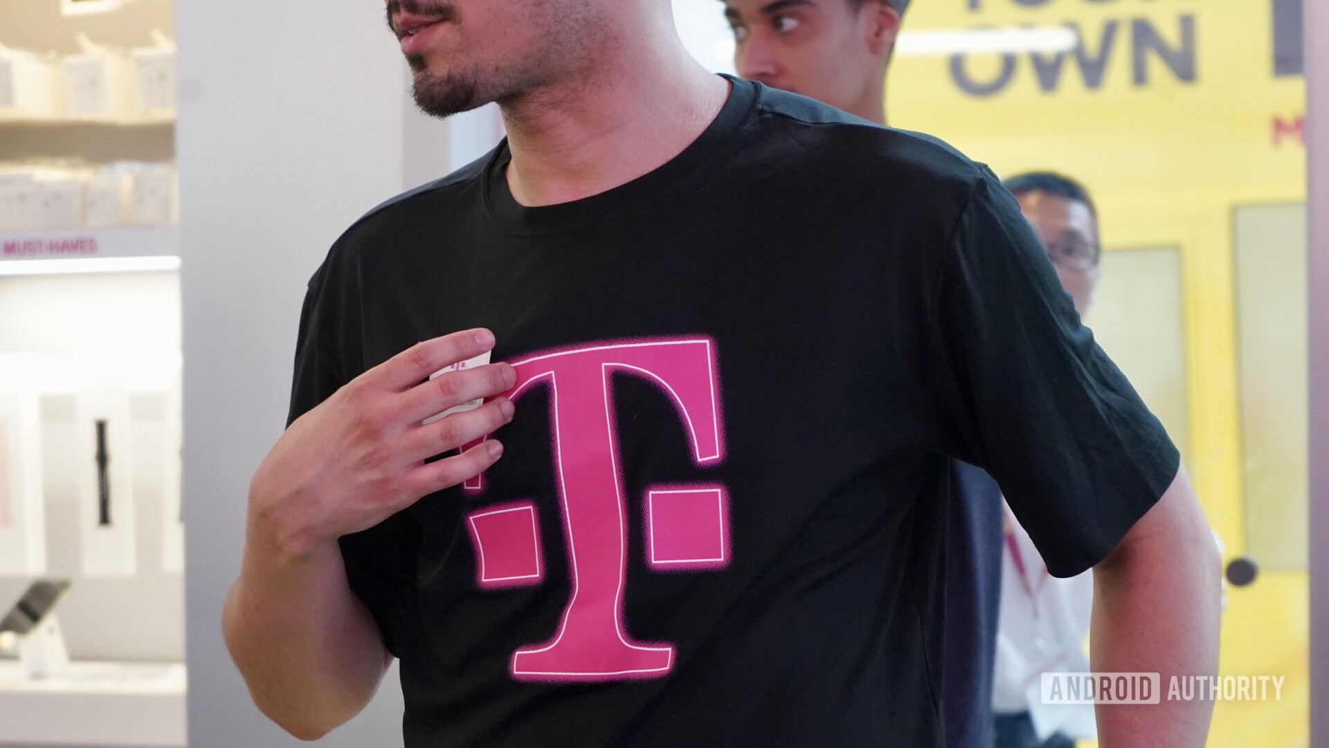 A T-Mobile employee selling T-Mobile 5G service while wearing a black t-shirt with the T-Mobile logo.