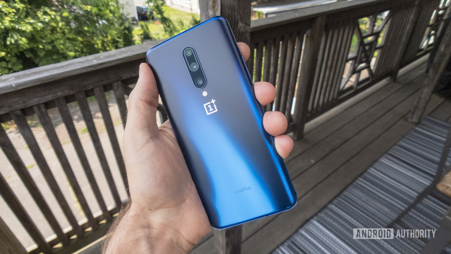 A hand holding a OnePlus 7 Pro so that you can see the back, which is the Nebula Blue color.