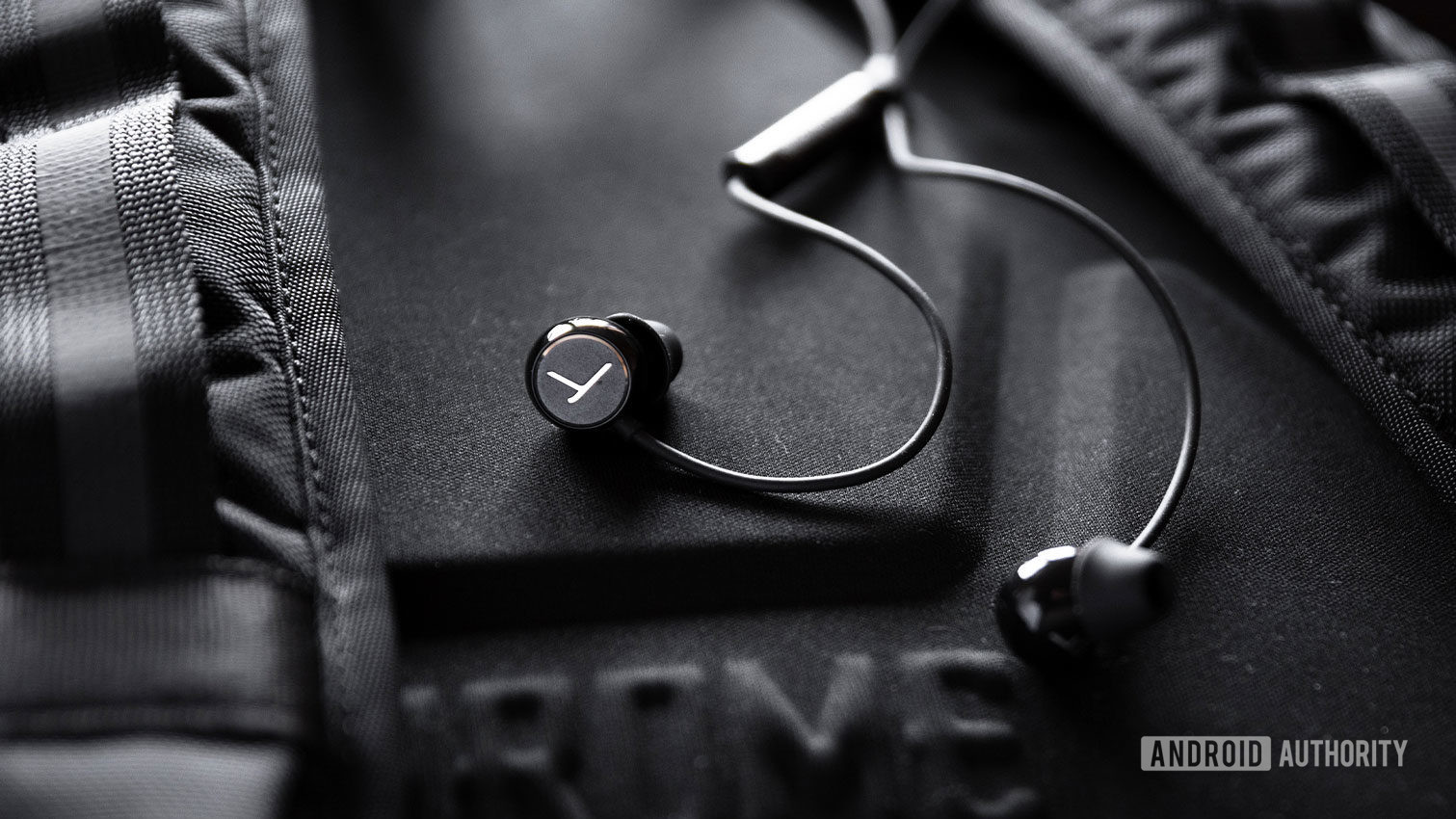 The Beyerdynamic Soul Byrd wired earphones in black against a black backpack.