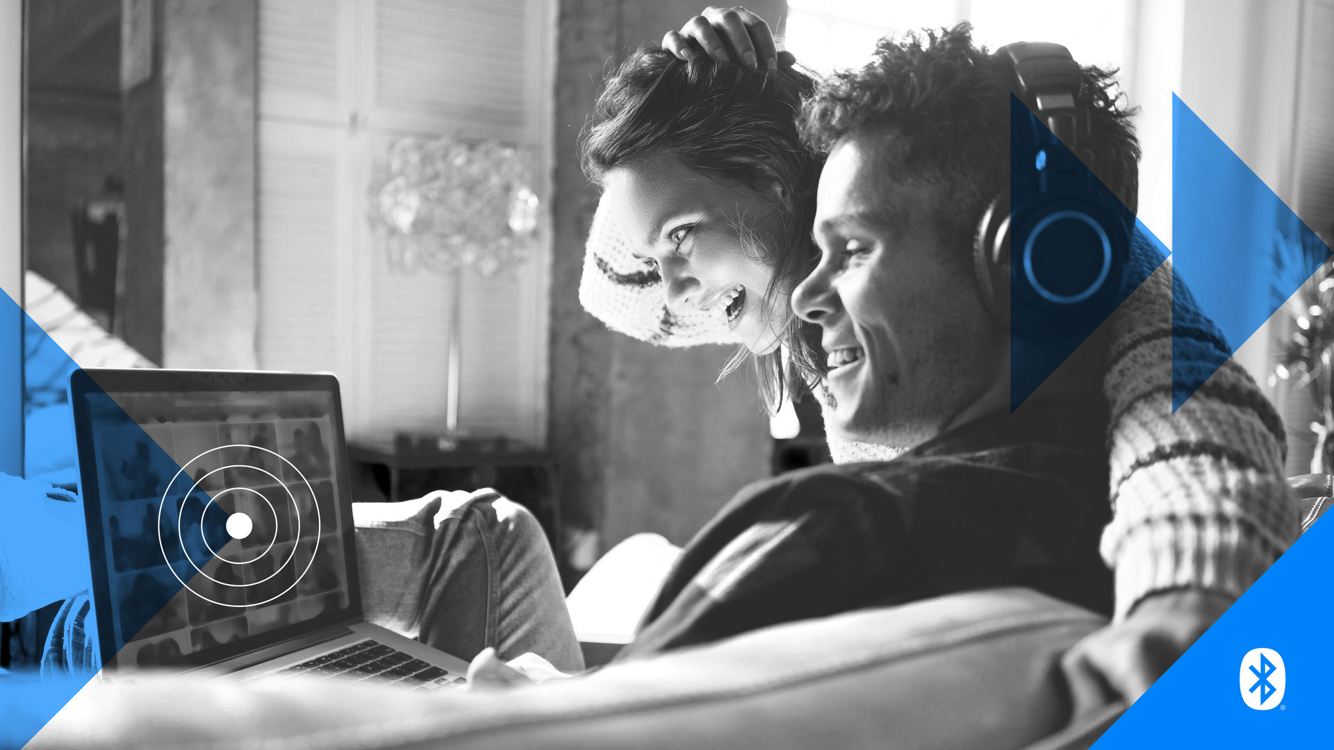 A picture of a man and a woman smiling at a laptop screen.