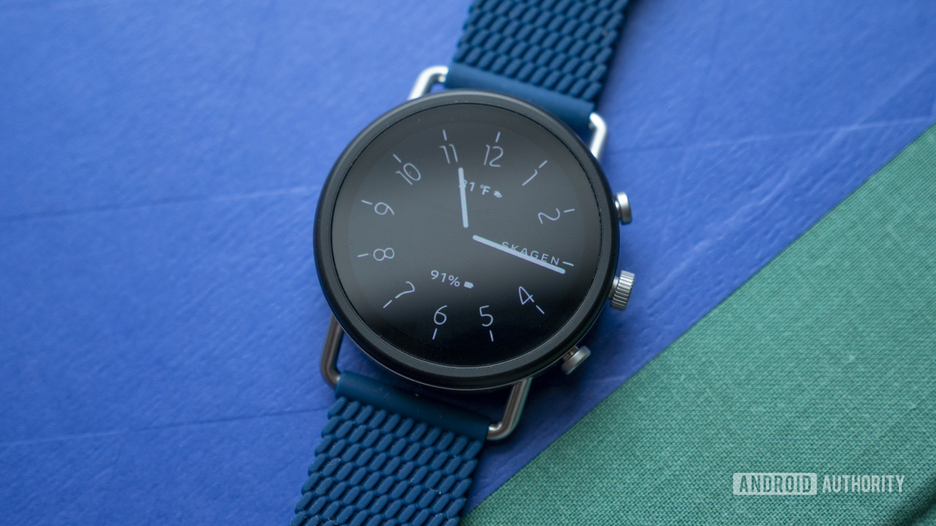 A Skagen Falster 3 rests on a green and blue book.