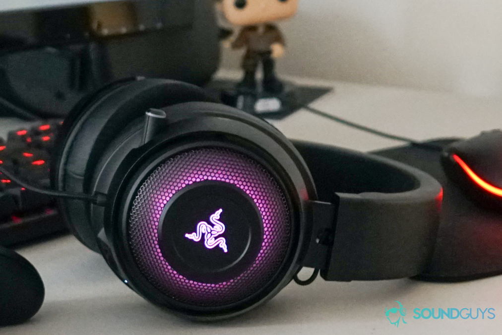 The Razer Kraken Ultimate lays in front of computer monitor and keyboard, as well as an oculus quest and a han solo doll.