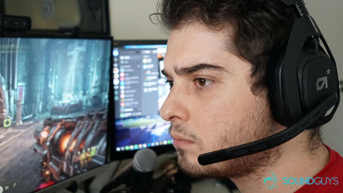 a man wearing the Astro Gaming A50 Wireless gaming headset sitting at a PC running Doom Eternal and Spotify