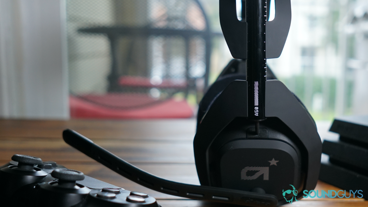 Astro Gaming A50 Wireless headset sits on a wooden table next to a Playstation 4 Pro and Dualshock 4 controller.