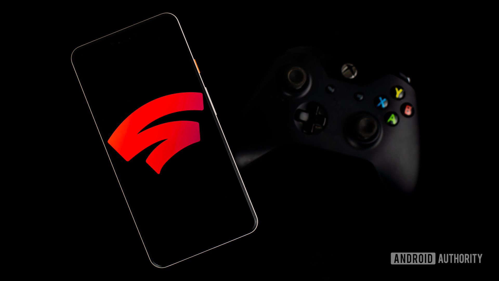 Google Stadia on smartphone next to gaming controller stock photo 1