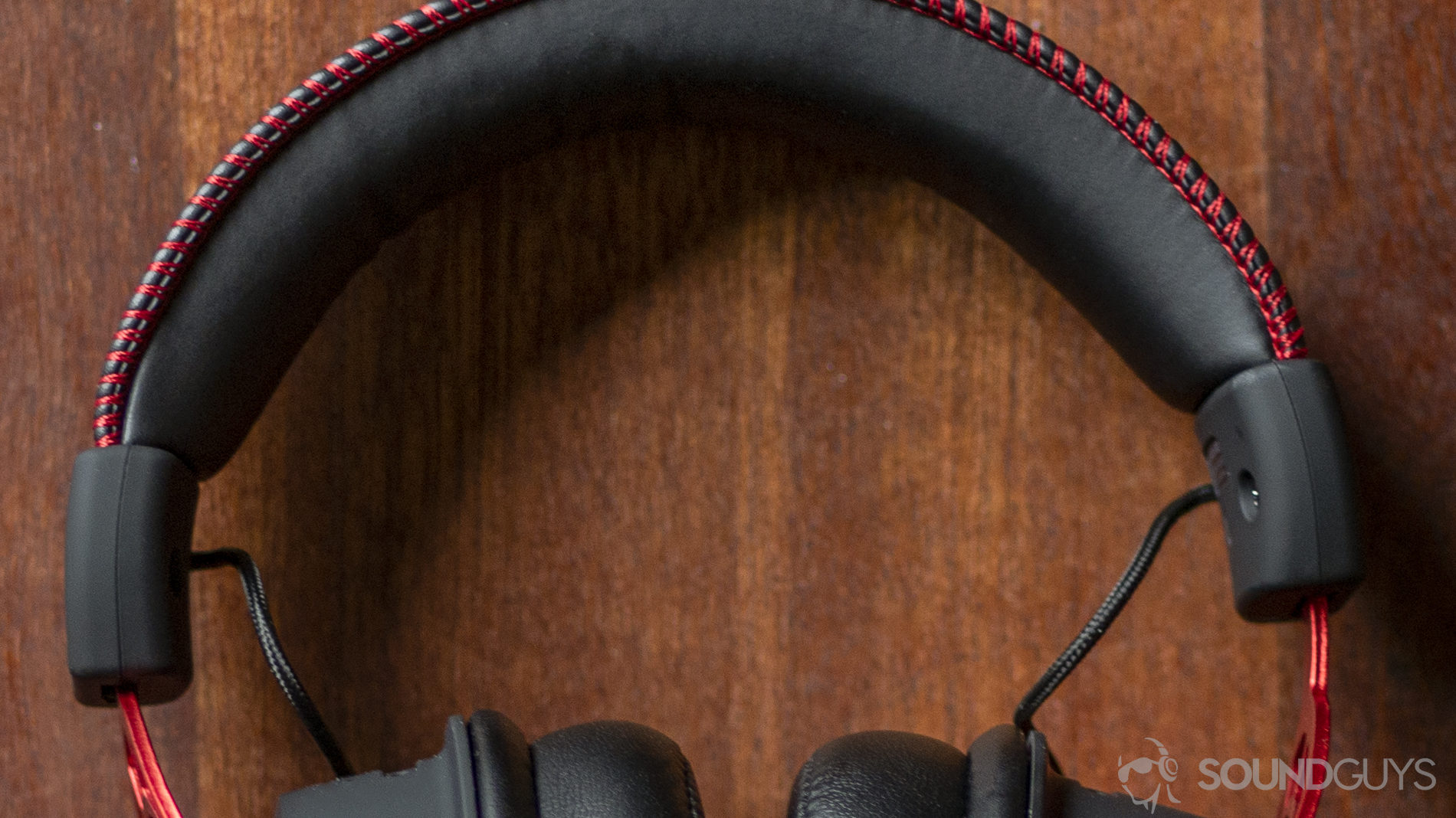 The HyperX Cloud Alpha lays on a wooden table, with the focus on its headband.