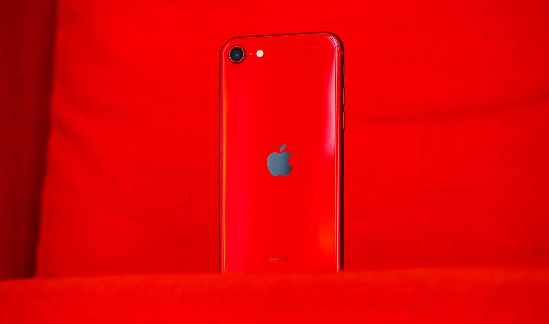 The iPhone SE in red showing the back Apple logo.