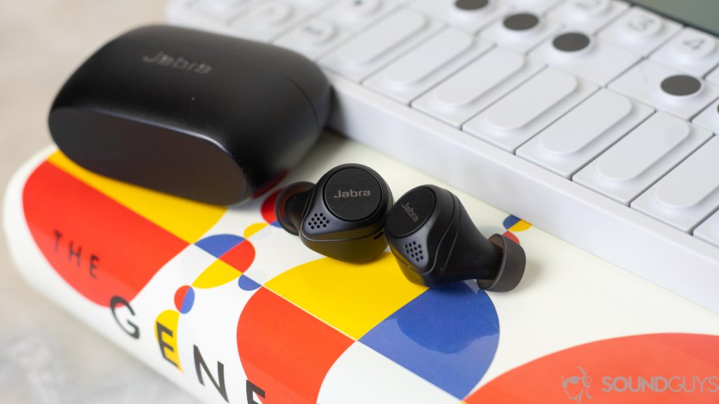 A picture of the Jabra Elite 75 earbuds on top of a book and next to synthesizer.