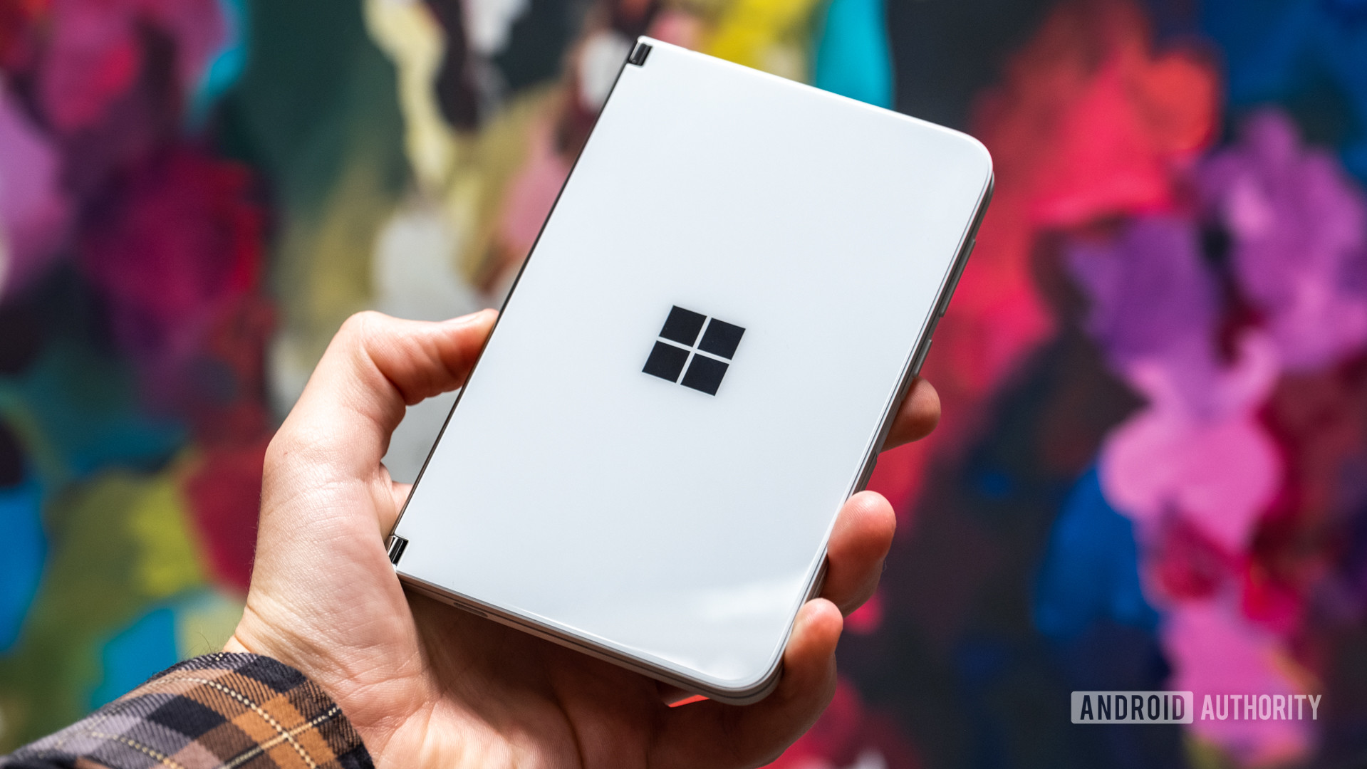 Microsoft Surface Duo closed in hand against backdrop