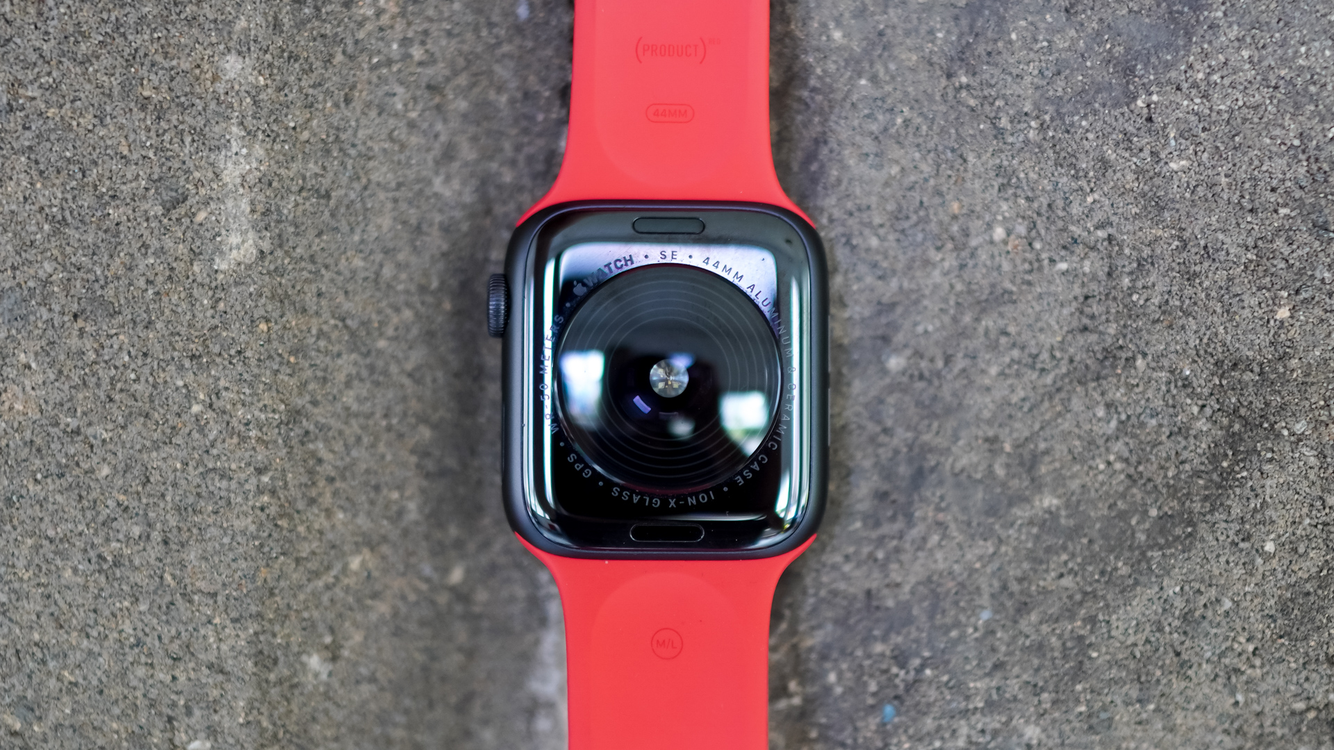 Une Apple Watch SE repose face vers le bas sur une surface en pierre affichant les capteurs à l'arrière de l'appareil.