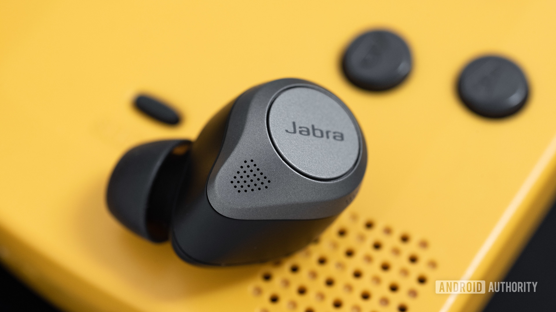 the jabra elite 85t noise cancelling true wireless earbuds microphone holes next to a gameboy color speaker grill.