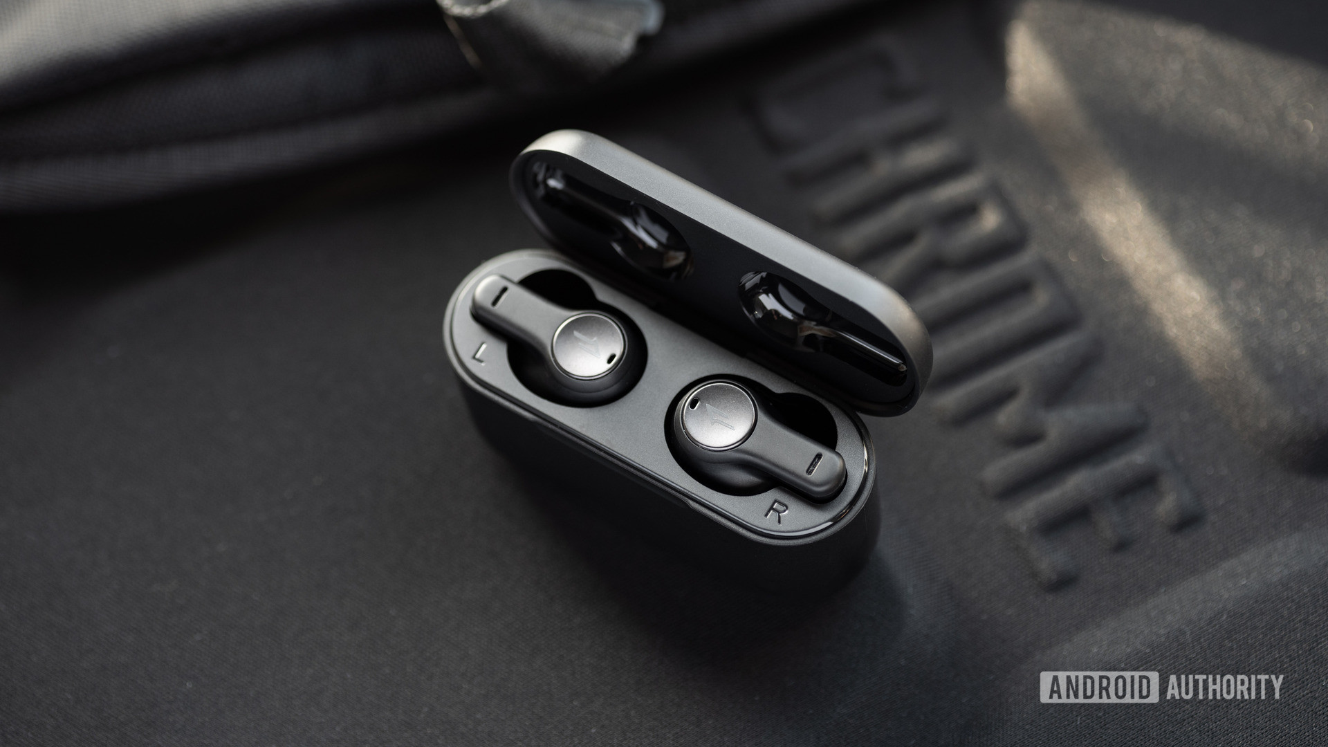 The 1MORE PistonBuds cheap true wireless earbuds sit in the open charging case against a black background.