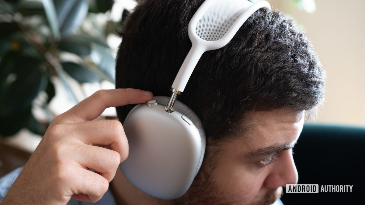 A man wears the Apple AirPods Max and uses the onboard headphone controls.
