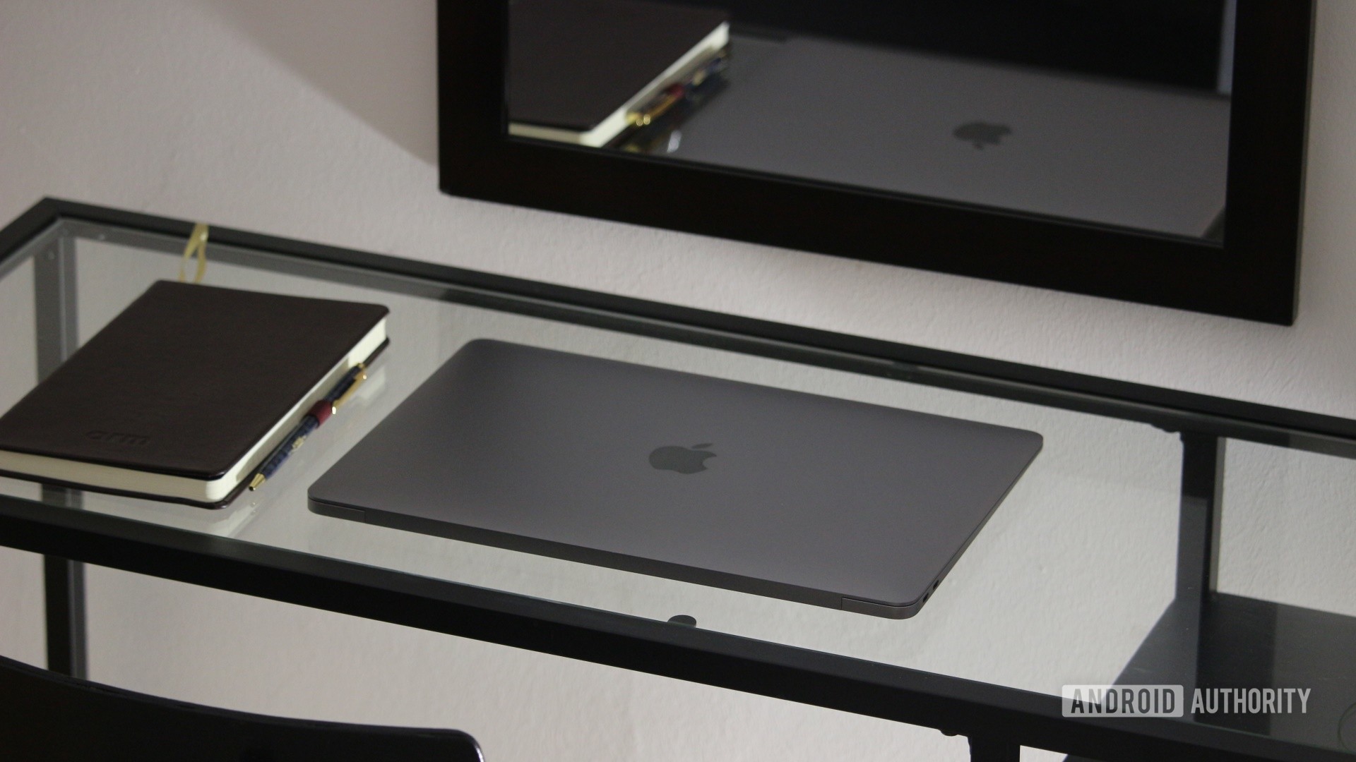 Apple MacBook Air M1 en un escritorio de cristal junto a un bloc de notas