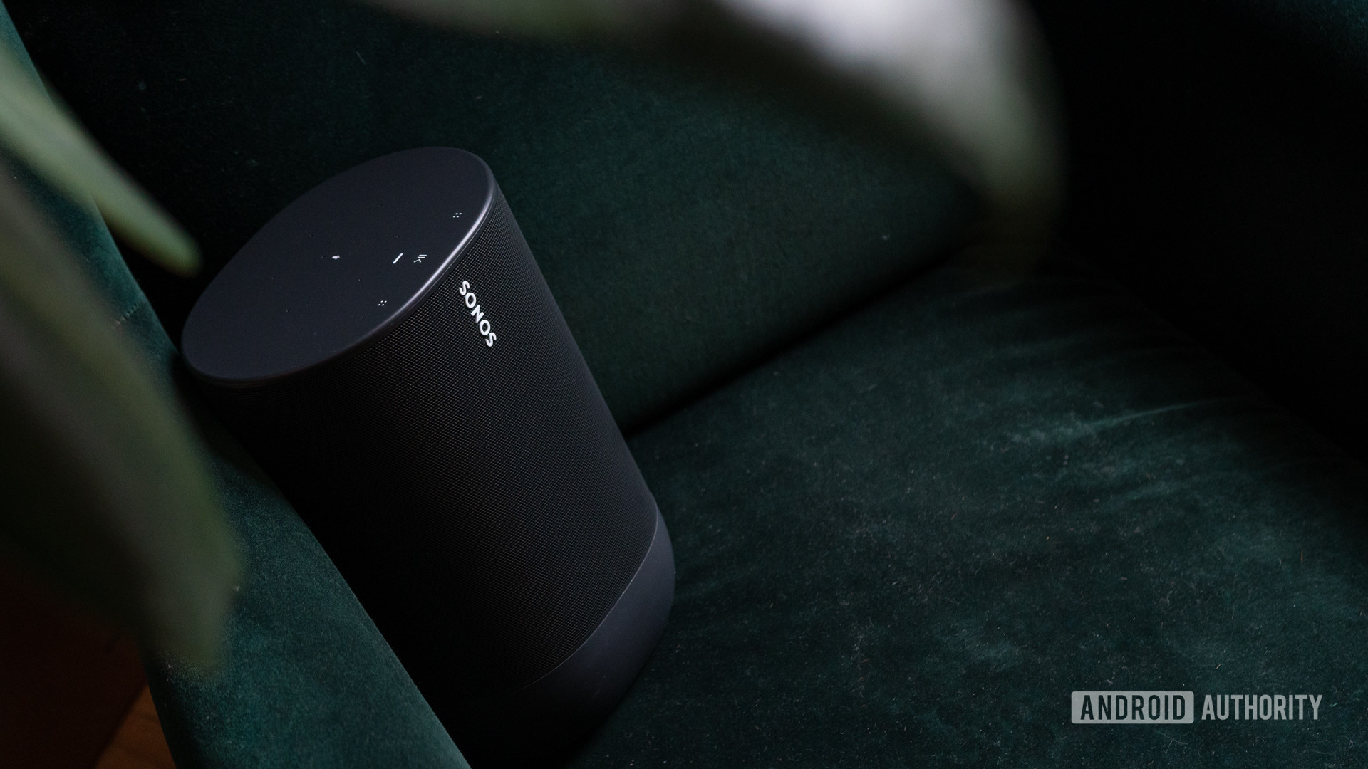 The Sonos Move Wi-Fi bluetooth smart speaker in black against a velvet couch.