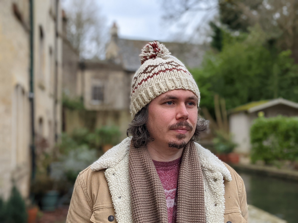 Portrait Outdoor Google Pixel 5 of a man with dark curly hair and facial hair wearing a woolly hat and a coat with a sheepskin collar
