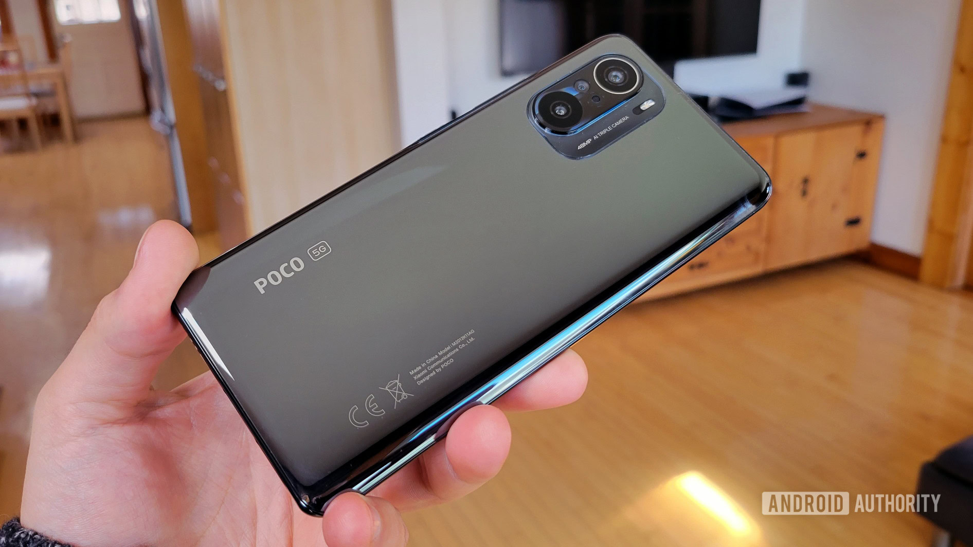 The back of the Poco F3 phone is in hand.