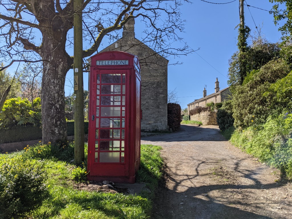 Google Pixel 5 camera color shot of a red phone booth on green grass