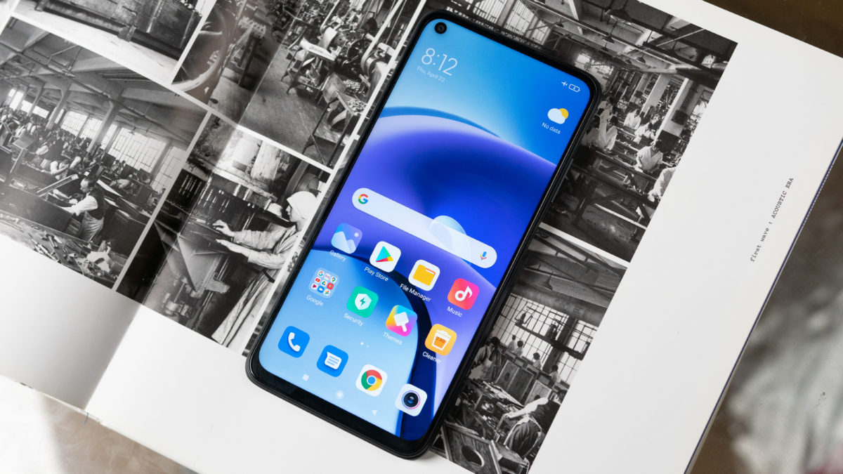 Xiaomi Redmi Note 9T with the screen turned on displaying the time lying flat on a black and white coffee table book.