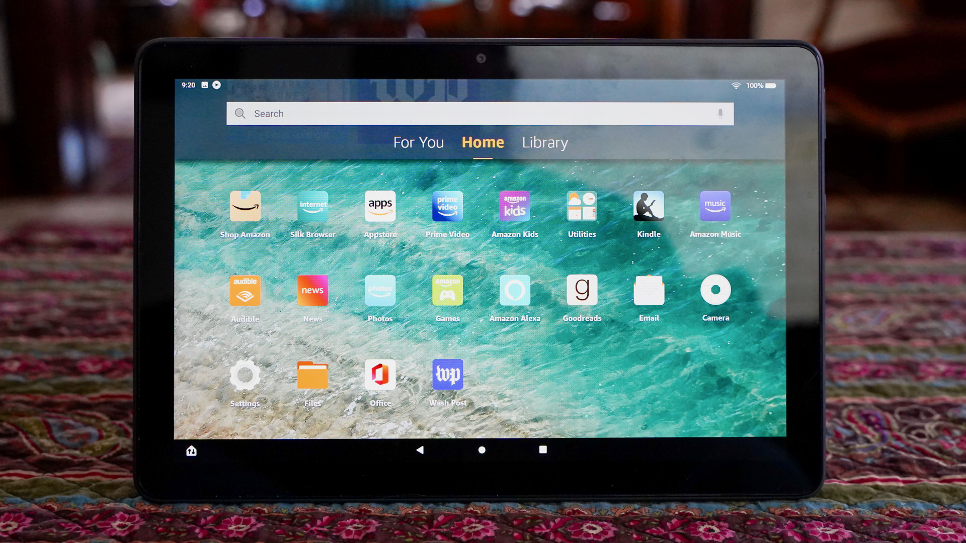 The Amazon Fire HD 10 Plus on a coffee table showing the home screen with apps.