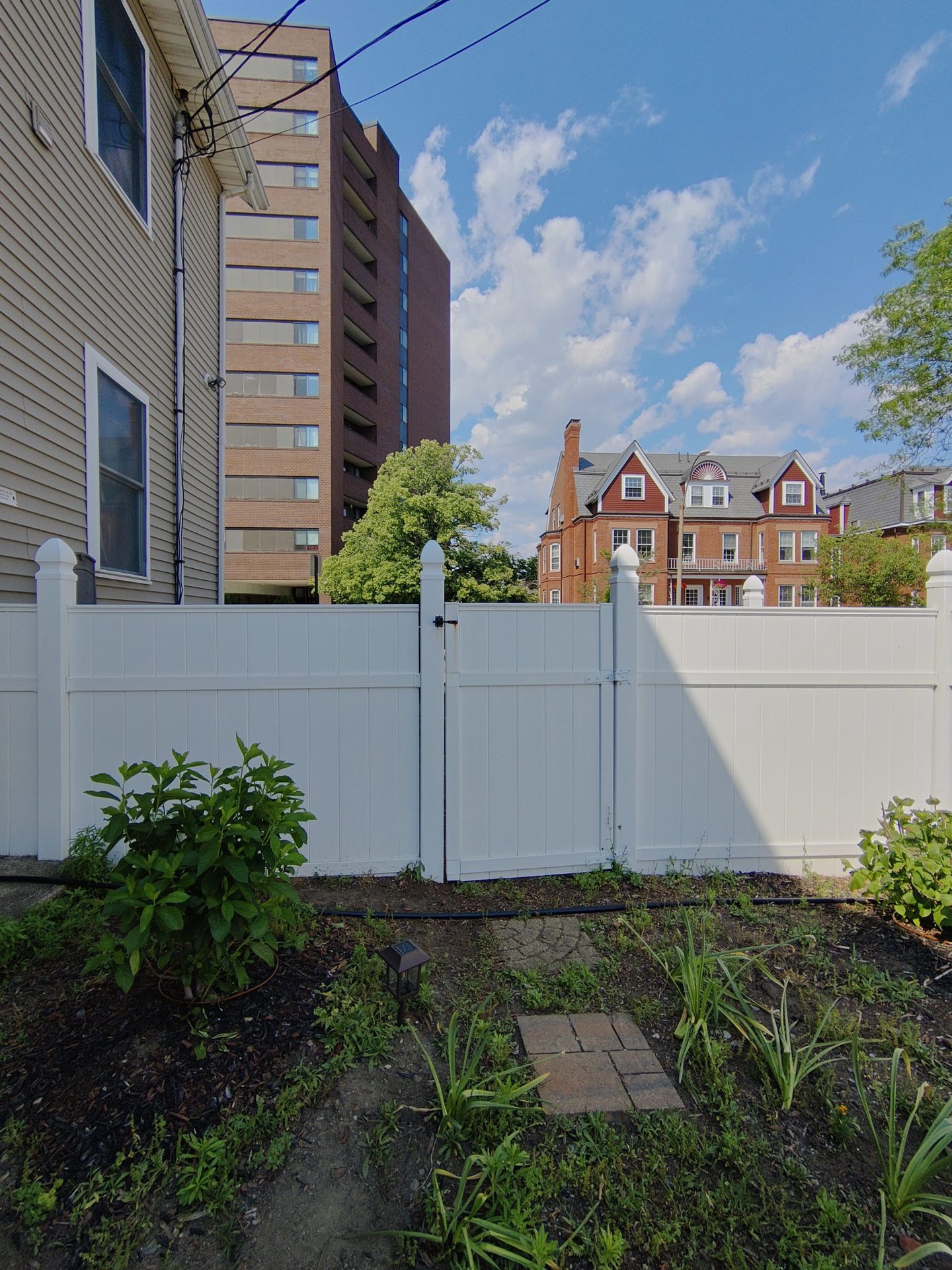 TCL 20 Pro 5G Ultrawide Camera shot of a garden and a white painted fence, with buildings visible in the distance.