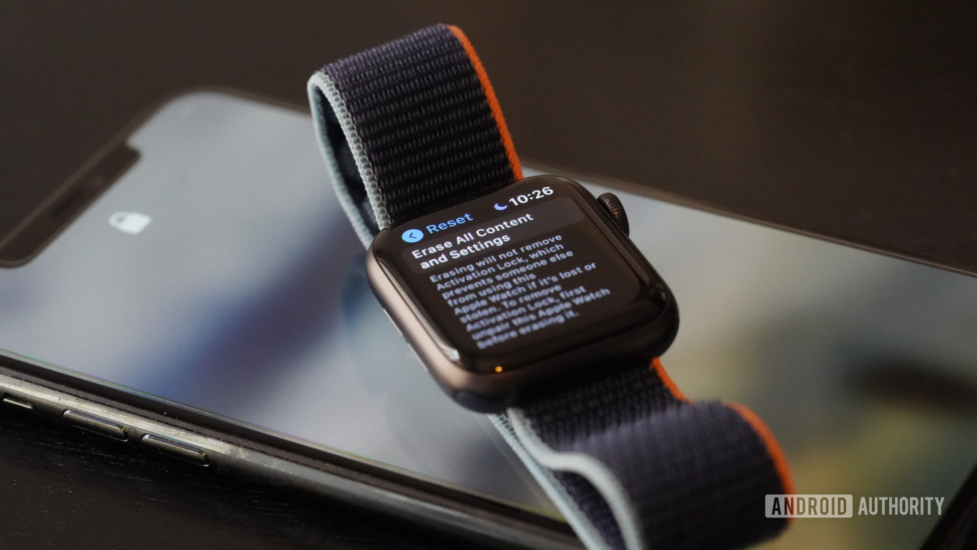 An Apple Watch 6 rests on an iPhone 11 displaying reset screen.