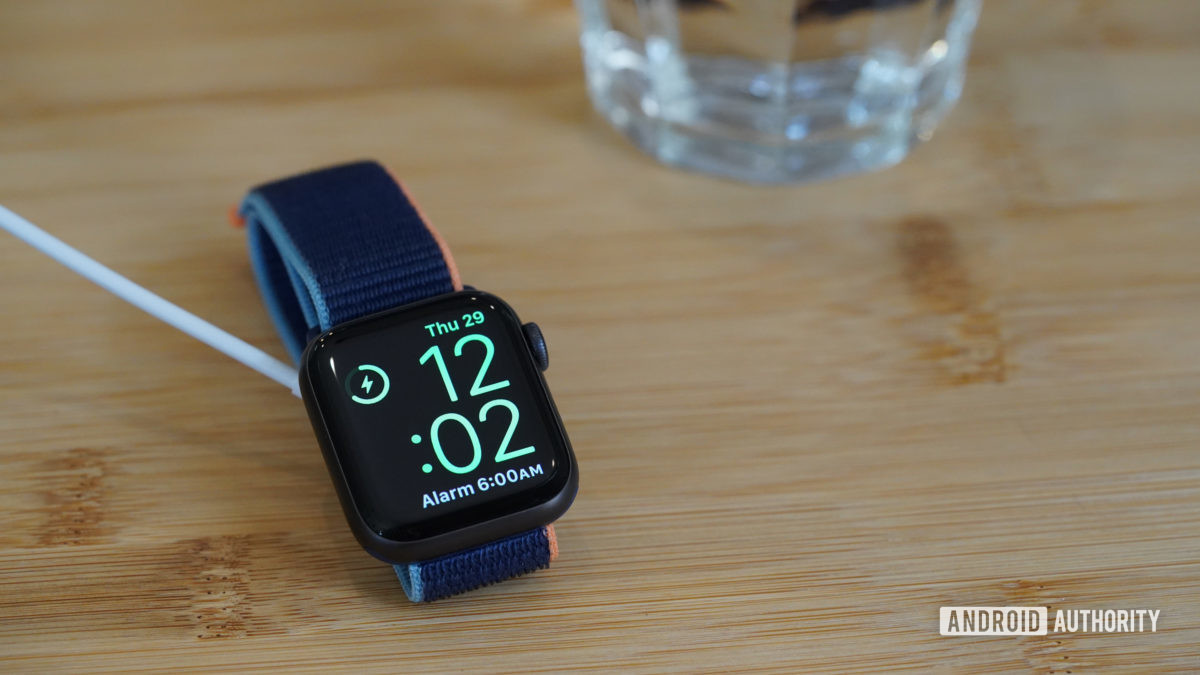 Charging Apple Watch Series 6 displays Nightstand mode on a bedside table