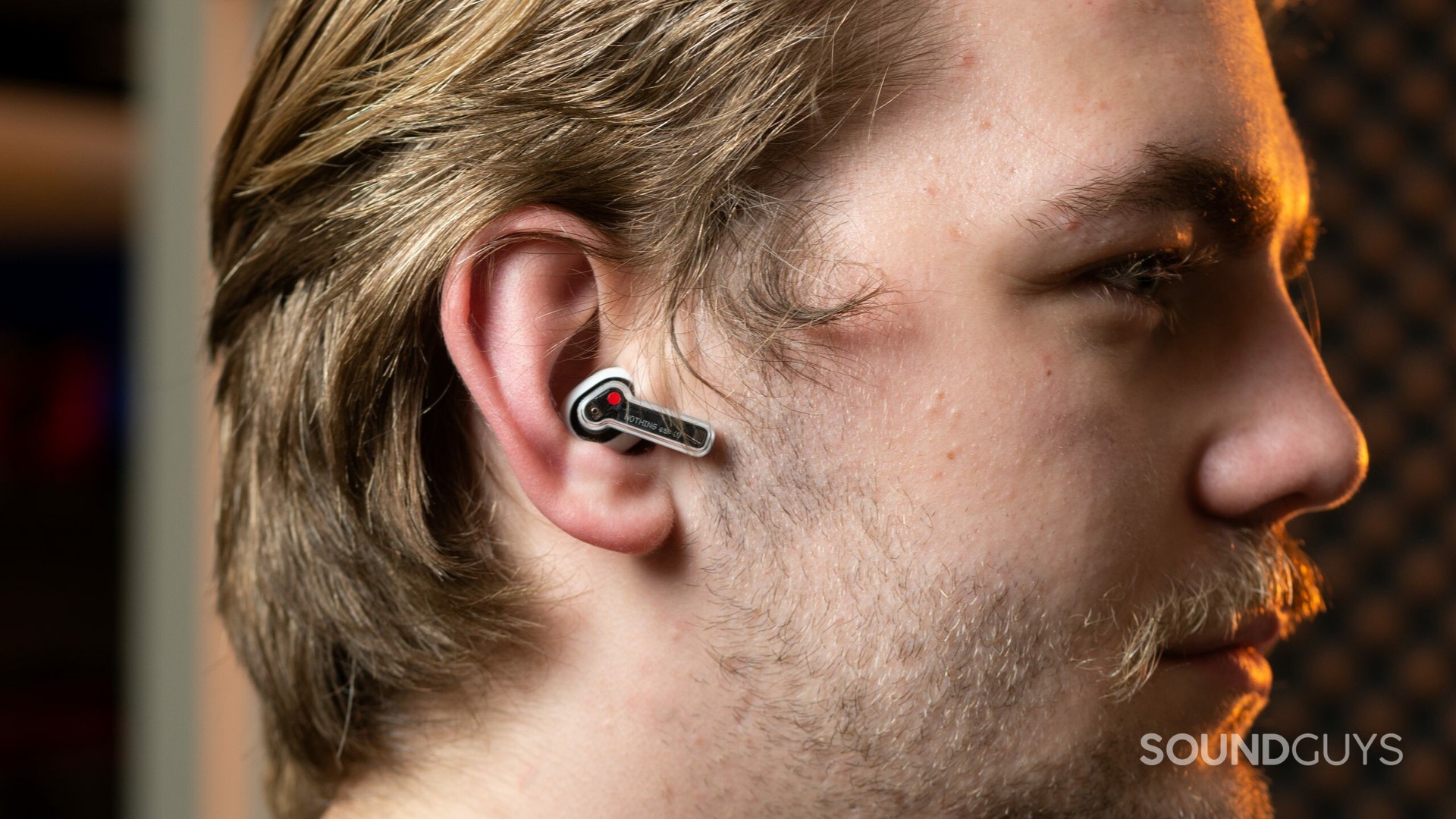 A burly man wears Nothing Ear 1 noise-canceling true wireless headphones.