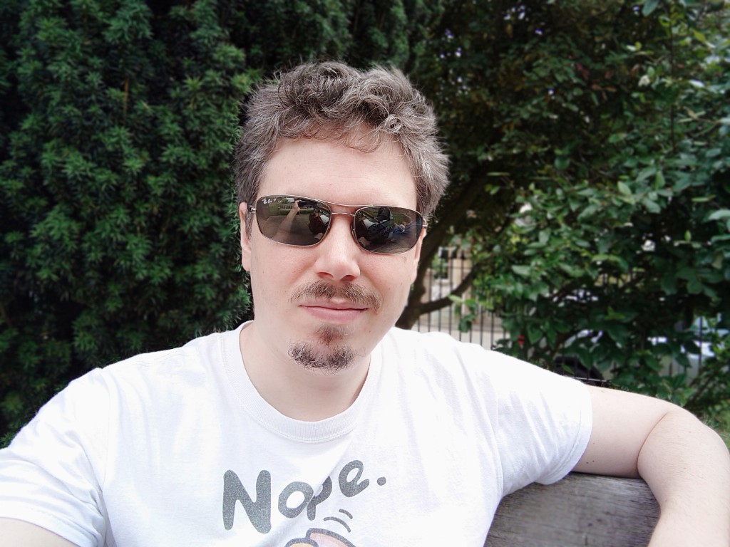 Sony Xperia 1 III Selfie Portrait of a man with brown hair wearing a white t-shirt and shades taken outside with trees behind him