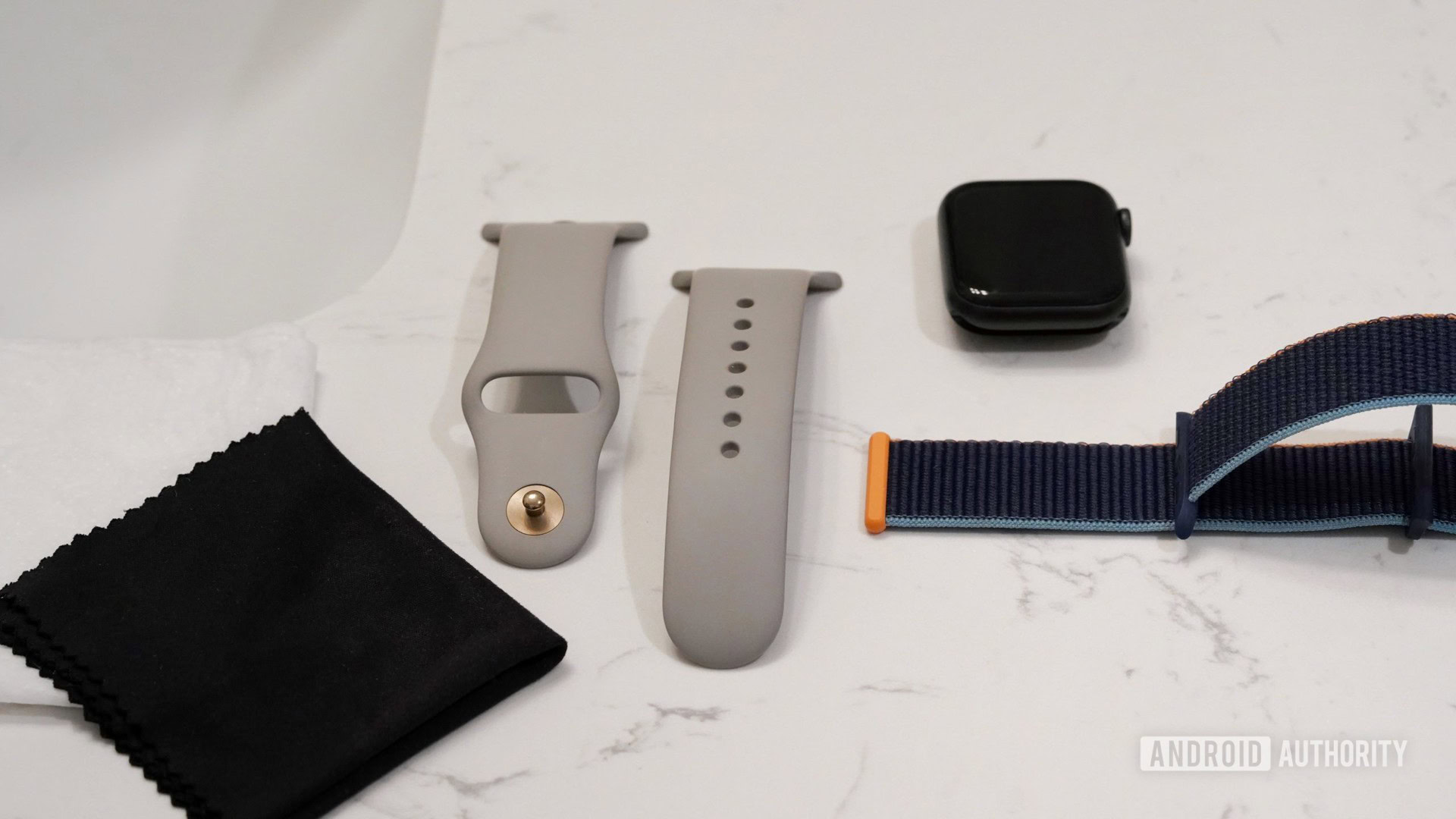 Apple Watch Series 6 et deux bracelets reposent sur un comptoir de salle de bain avec des vêtements nécessaires pour nettoyer les bracelets Apple Watch