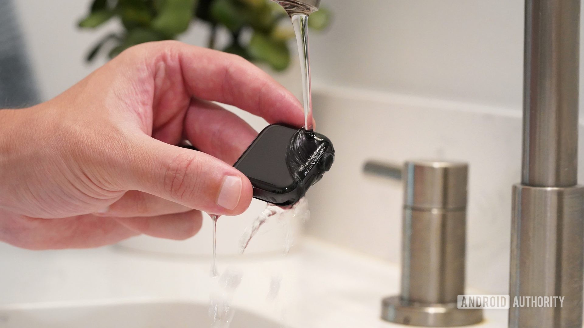 Une main masculine tient l'Apple Watch Series 6 sous de l'eau tiède à faible débit pour nettoyer l'appareil.