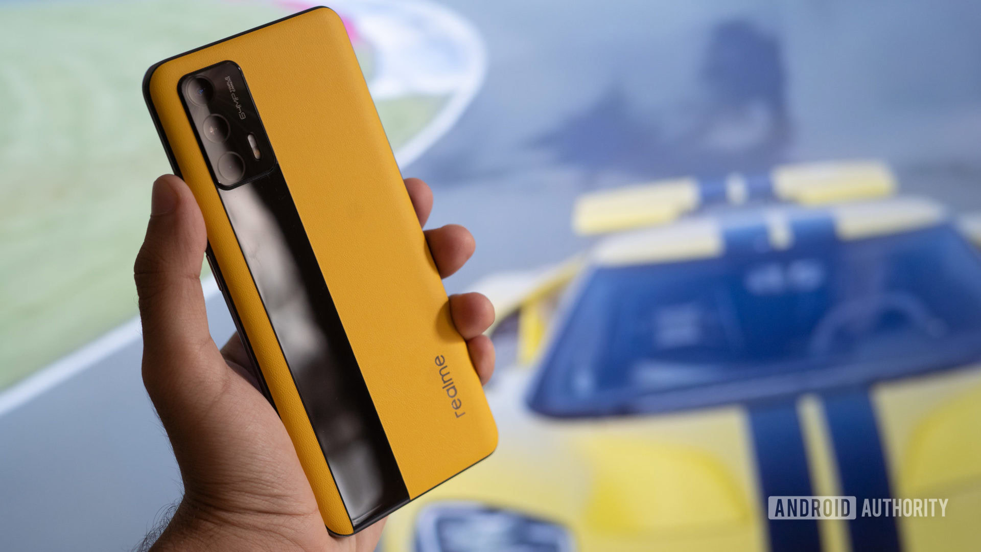 Realme GT in hand with race car behind it