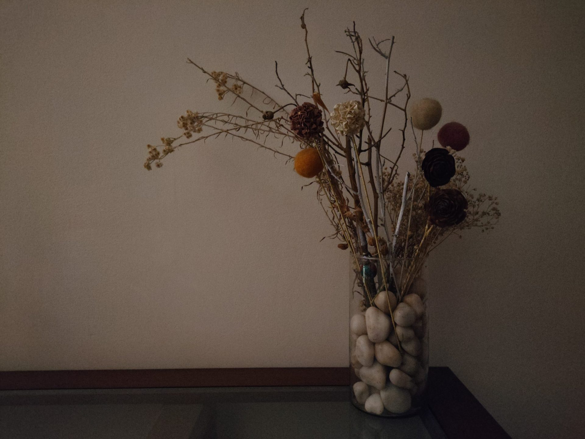 Realme GT low light shot of dried grasses and flowers in a vase with pebbles.