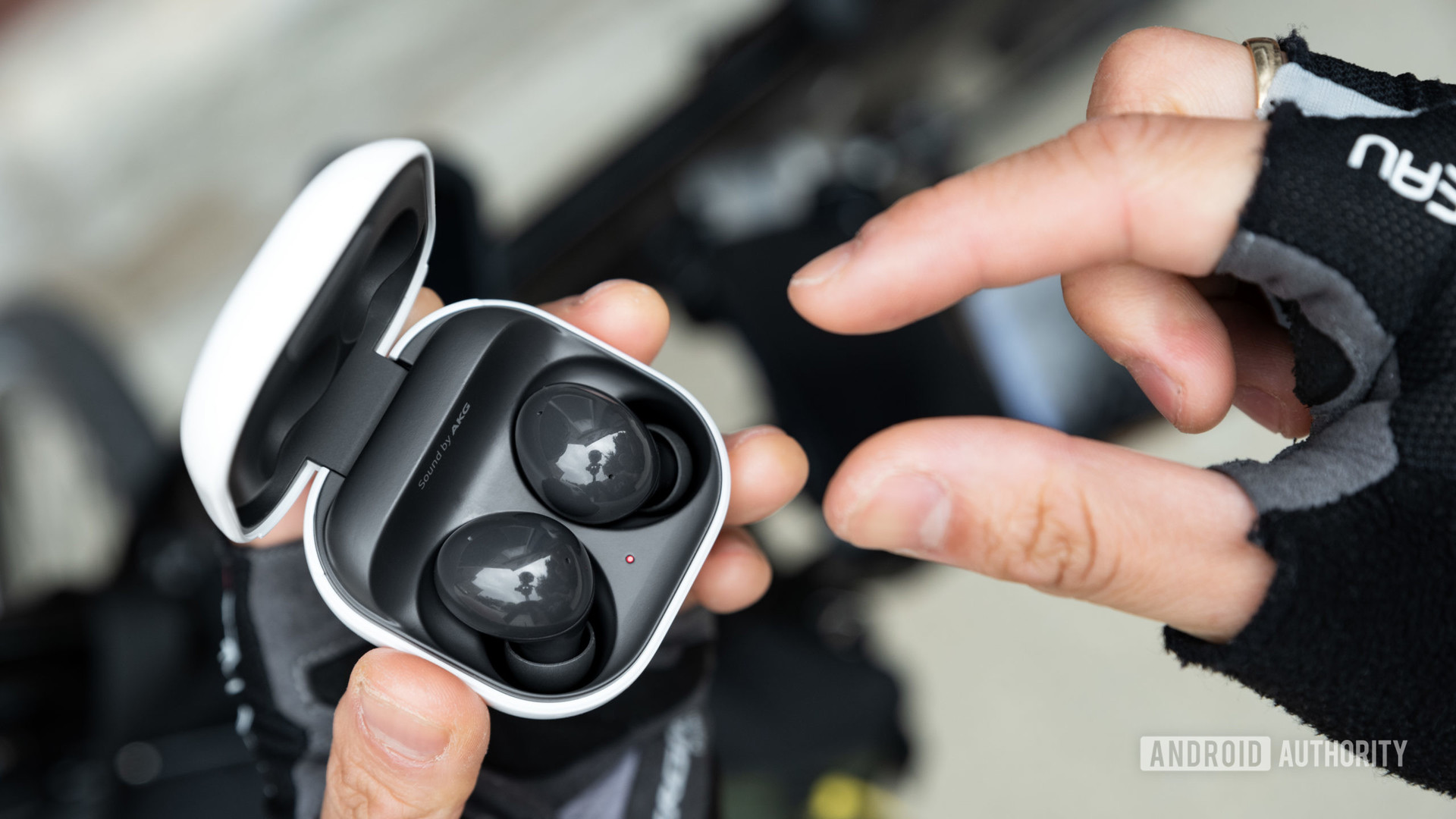 A hand reaches to remove one Samsung Galaxy Buds 2 noise cancelling true wireless 2 earbud from the case.