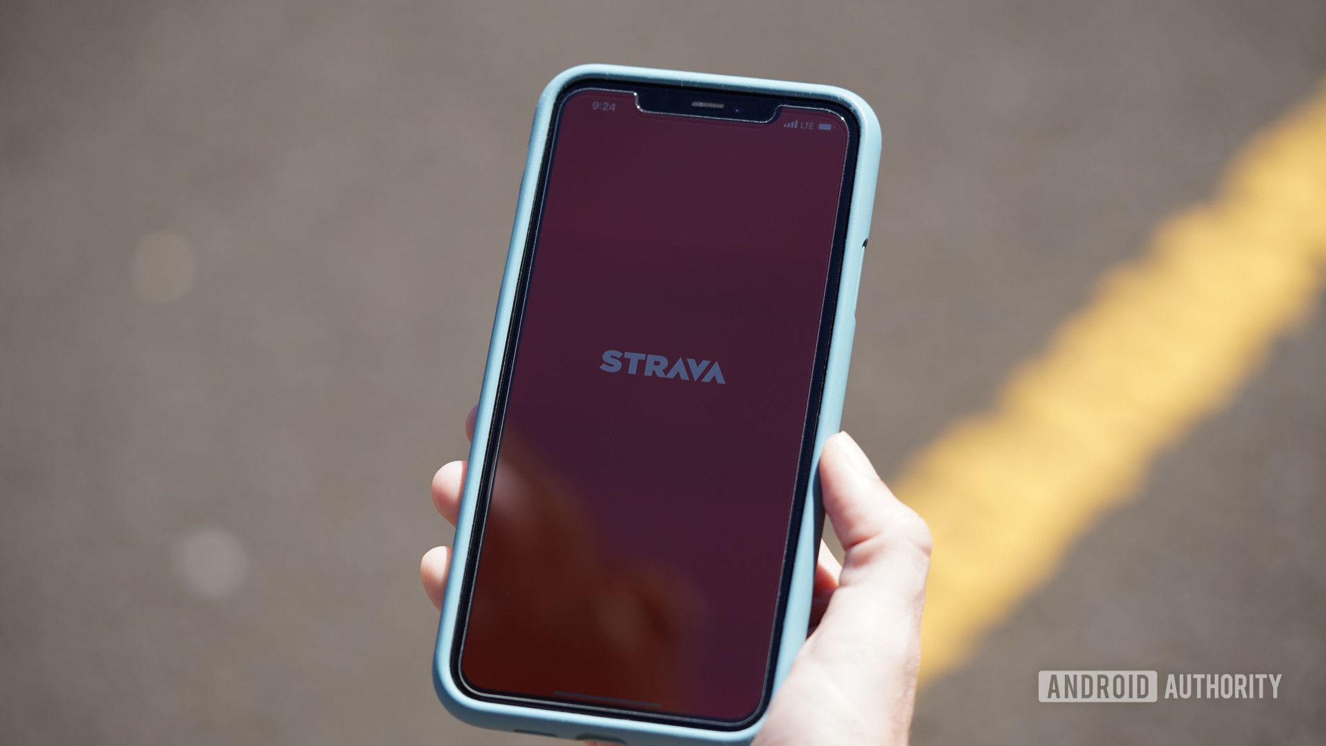 A female runner opens the Strava mobile app on their iPhone 11.